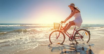 Frau auf einem Fahrrad auf Reisen am Strand