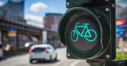 Eine Ampel für Fahrradfahrer an einer befahrenen Straße zeigt grünes Licht.