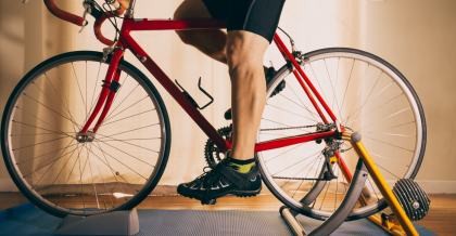 Mann auf einem Fahrrad sitzend, welches in einem Rollentrainer eingesetzt ist.