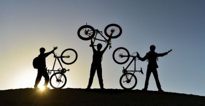 Drei Fahrradfahrer präsentieren ihr Fahrrad als Zeichen für den Klimaschutz.