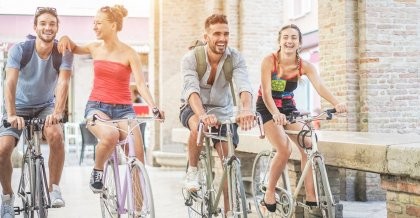 Zwei Fahrradfahrer stehen im Sonnenuntergang und halten ihre Fahrräder in die Höhe.