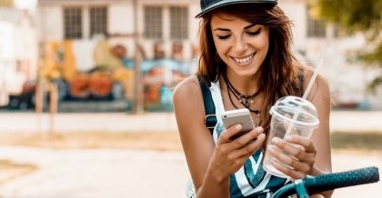 Eine junge Frau benutzt ihr Handy am Fahrrad als Navi und Fitness-Tracker.