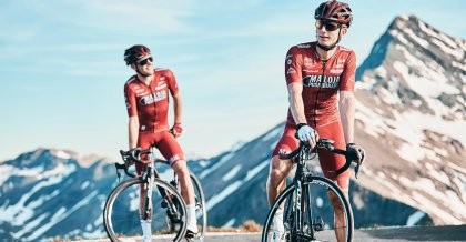 Zwei Radfahrer der Tour de France stehen vor den Alpen.