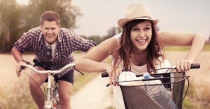 Zwei junge Menschen fahren auf dem Fahrrad mit ihrem Fahrradzubehör durch die Natur.