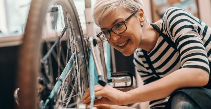 Frau mit Brille bastelt an einem türkisen Fahrrad